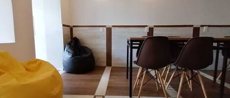Een moderne eethoek met een houten vloer, een gele relaxfauteuil en een tafel met vier stoelen.