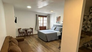Un espacio habitable compacto con sofá, cama, zona de comedor y pequeña cocina.