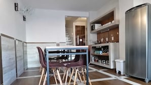 Una cocina moderna con una mesa de comedor y sillas, un refrigerador y una escalera que sube a otro nivel.