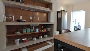 Una cocina con microondas, estantes con utensilios de cocina, un lavabo y una mesa de comedor.