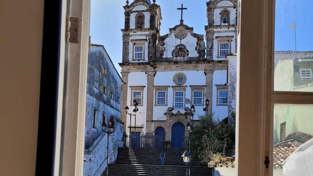 Vista de una iglesia histórica con un campanario y una escalera que la conduce.
