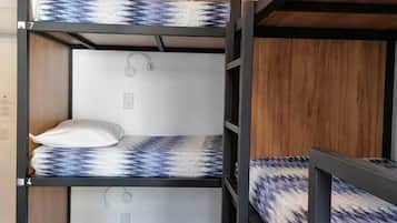 Habitación con literas de tres niveles, cada una con colchones y almohadas estampadas.