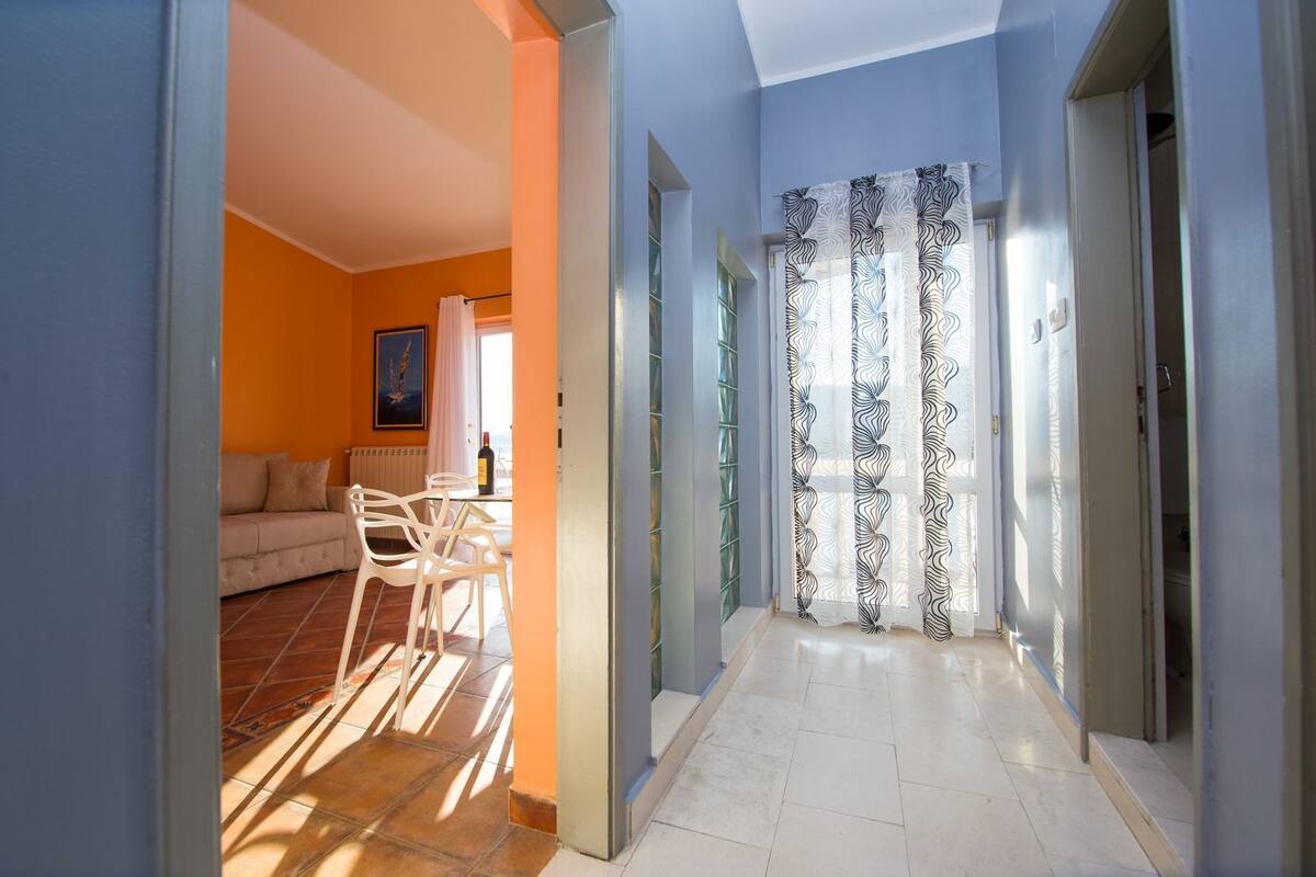 Um corredor com área de refeições, um sofá e vista para o exterior.
