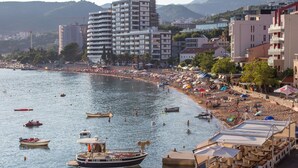 A coastal area with a beach, boats, and buildings. - ACIKA apartments Rafailovici (Becici)