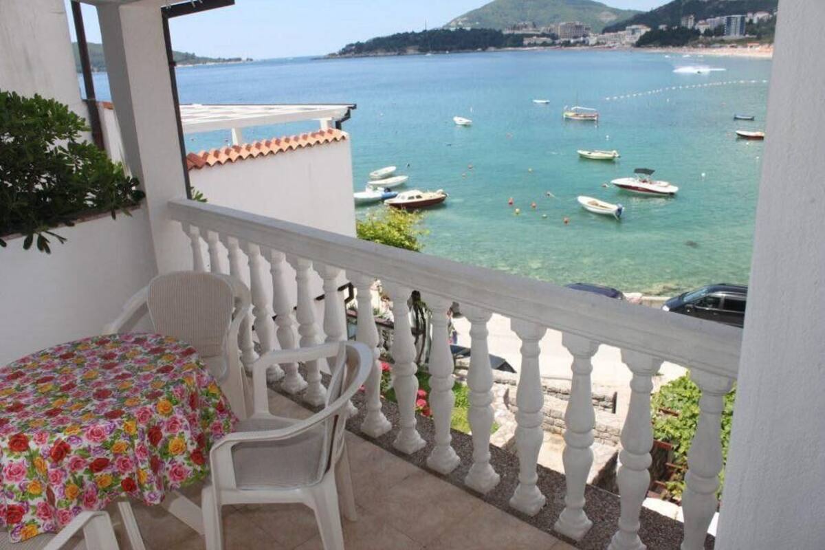 Varanda com mesa e cadeiras com vista para a área costeira e barcos.