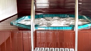 Un espace de détente en bois avec un bain à remous en verre et une échelle en métal.