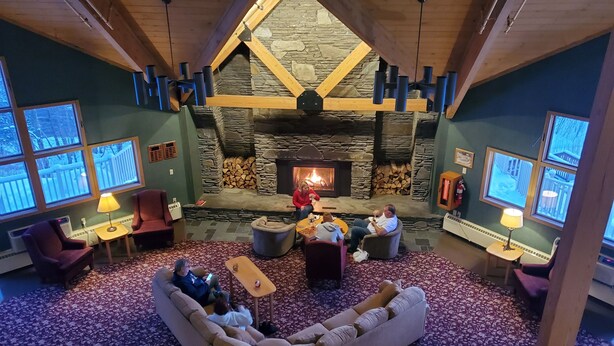 A cozy lodge interior with a stone fireplace, wooden beams, and a large seating area. - ESCAPE TO THE PERFECT WHITE MOUNTAIN LOCATION - Cozy Condo @ Lincoln Station (Lincoln)
