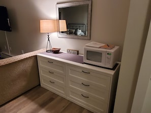A small kitchenette with a microwave, a lamp, and a bowl on the counter.