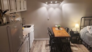 A compact kitchen with white cabinets, a wooden dining table, and a bed with a metal frame. - ESCAPE TO THE PERFECT WHITE MOUNTAIN LOCATION - Cozy Condo @ Lincoln Station (Lincoln)