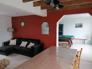 Relax in this stylish living room with a sofa, dining table, and pool table.