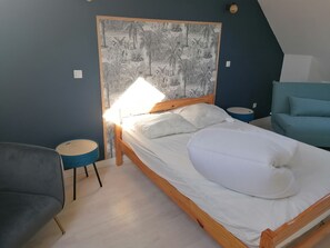 Relax in this serene bedroom with a comfortable bed, a wall-mounted mural, and a stylish seating area.