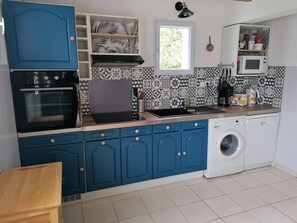 Compact kitchen with oven, microwave, and sink, plus a washing machine and window above.