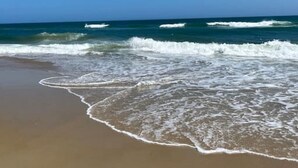 Una playa con olas acercándose a la orilla bajo un cielo azul despejado.