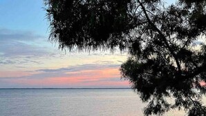 Vista de un mar tranquilo al atardecer, con una cubierta de madera en primer plano.