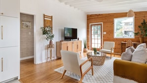 Una sala de estar moderna con televisor, armarios de madera, un sofá y un comedor.
