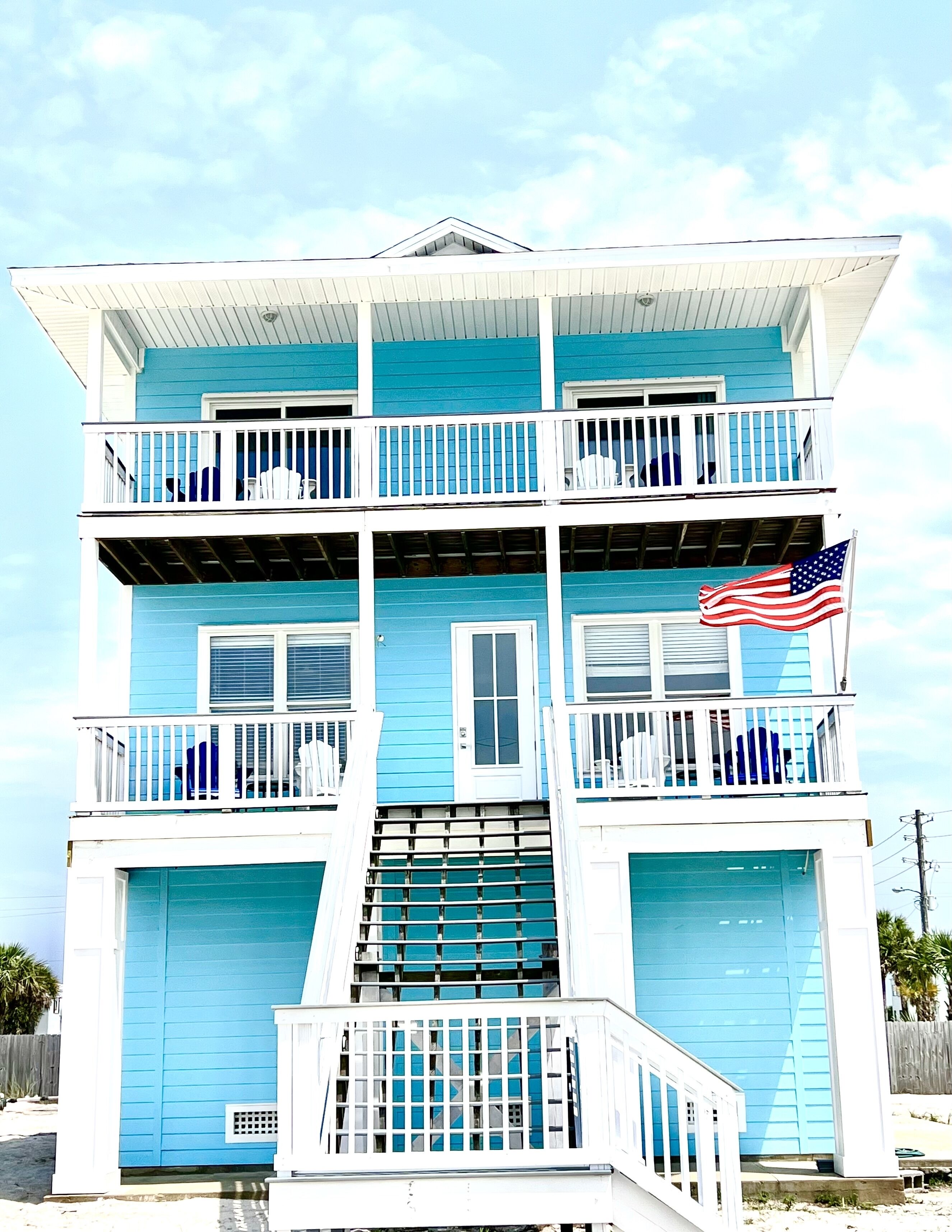 A multi-story building with a blue exterior, white railings, and an American flag.