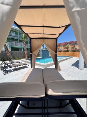 Relax by the pool in a shaded lounge area with a clear view of the water.
