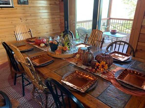 A wooden dining table set with copper serving trays, pumpkins, and autumn decorations.