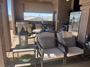 Un patio al aire libre con una parrilla, zona de estar y un refrigerador.