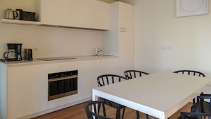 A compact kitchen with a built-in oven, a coffee maker, and a sink. There is a dining table with chairs. - Villa Ada & Rico, 500 meters from the village lake view pool and hydromasage (Veneto)