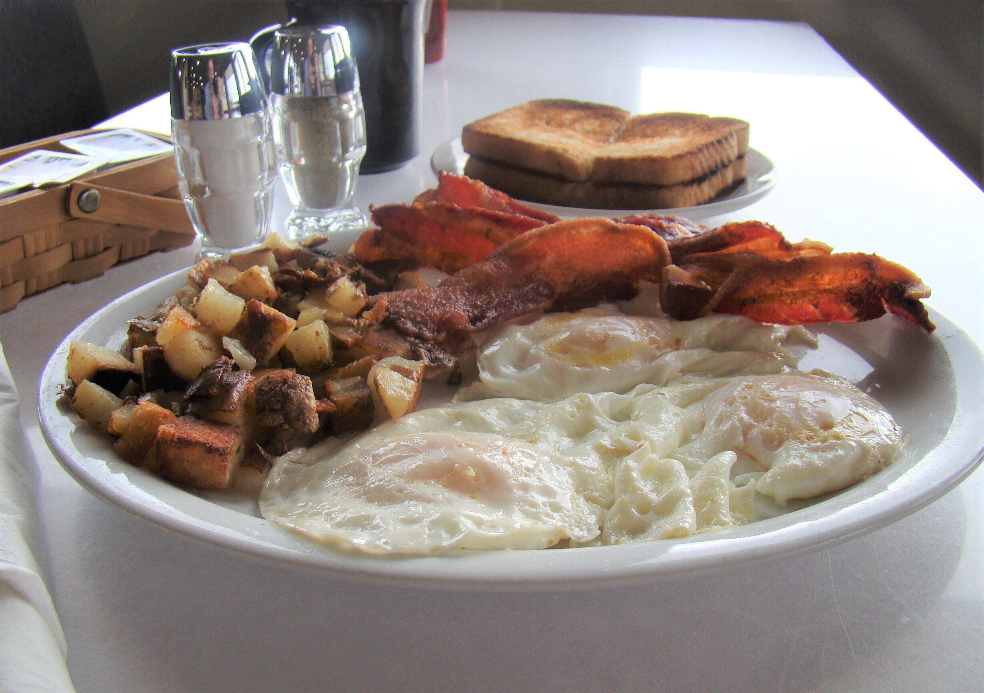 A plate of breakfast food including eggs, bacon, and toast.