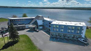 A multi-story hotel with a parking lot and a view of a lake.