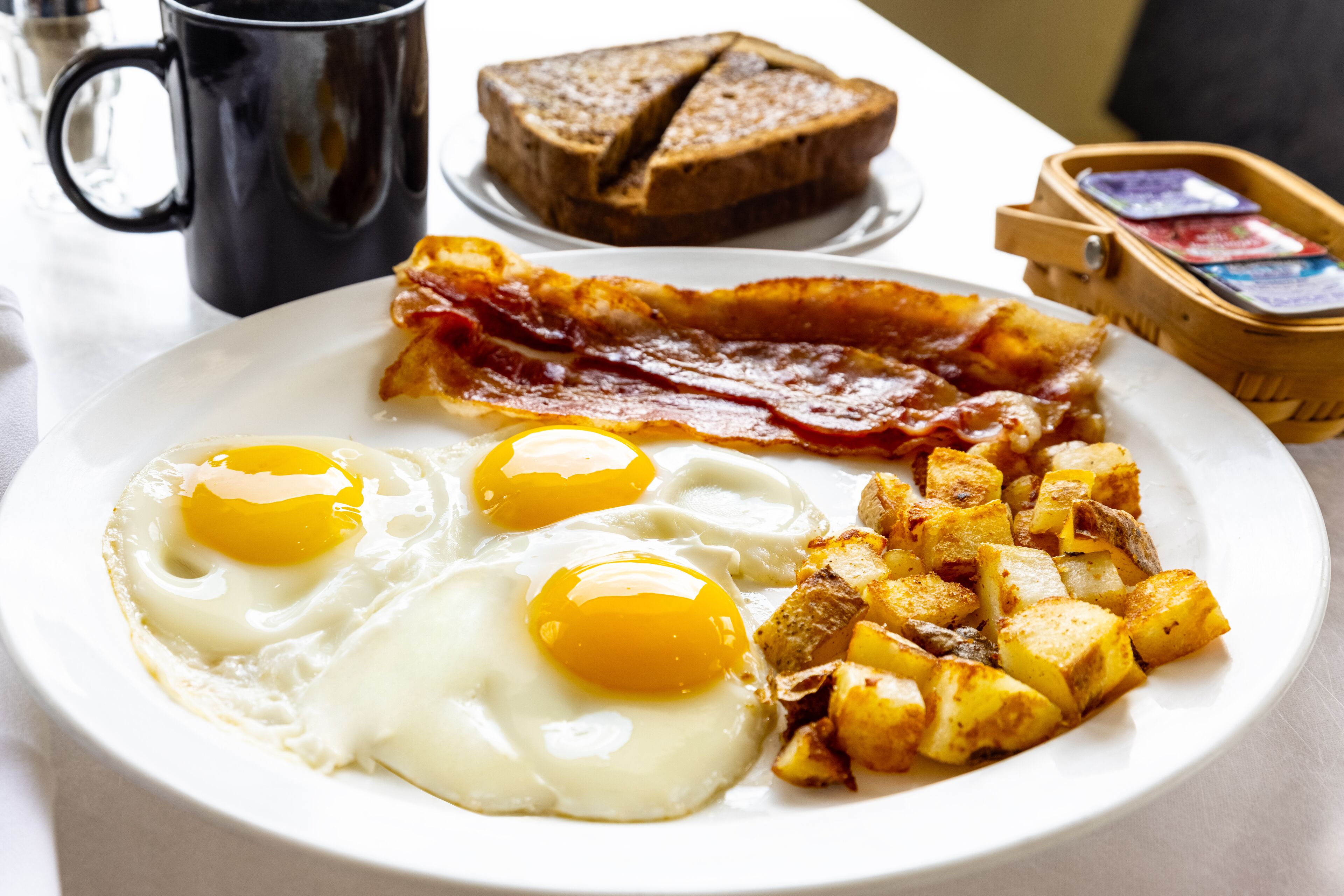 A breakfast plate with eggs, bacon, and potatoes.