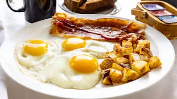 A breakfast plate with eggs, bacon, and potatoes.
