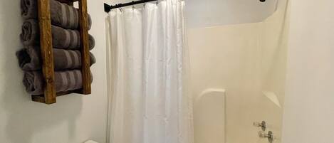 Une salle de bain avec une douche, des toilettes et une étagère avec des serviettes.