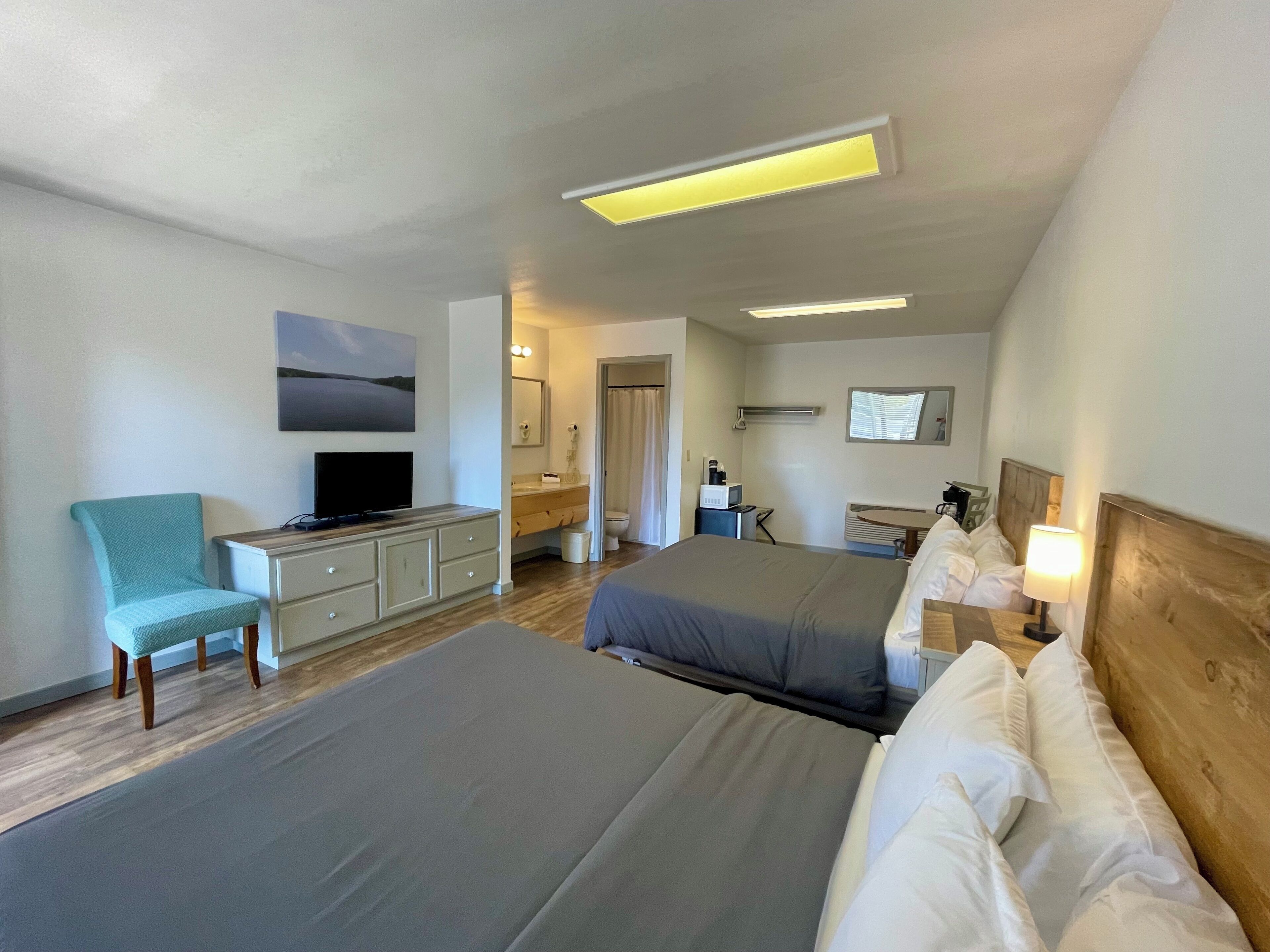 A hotel room with two beds, a TV, a desk, and a chair.