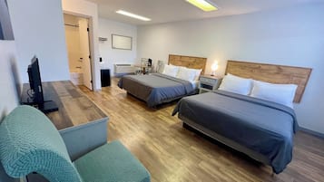 Habitación de hotel con dos camas, un escritorio, una silla y un televisor.