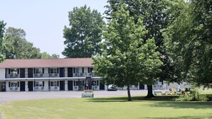 A motel with a two-story structure, a parking lot, and a grassy area with outdoor seating. - The Klassic Inn (Higden)