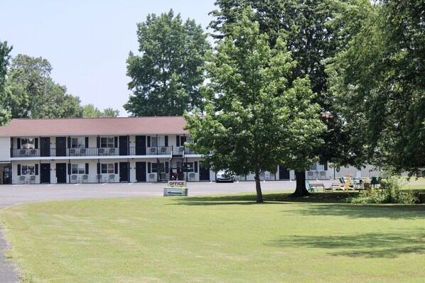 A motel with a two-story structure, a parking lot, and a grassy area with outdoor seating.