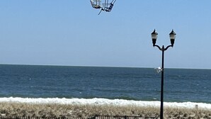 Vista de la playa con un paseo marítimo de madera, un farol y un cartel.