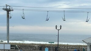 Un balcón con vista al océano, una cerca blanca, una mesa pequeña y una silla.