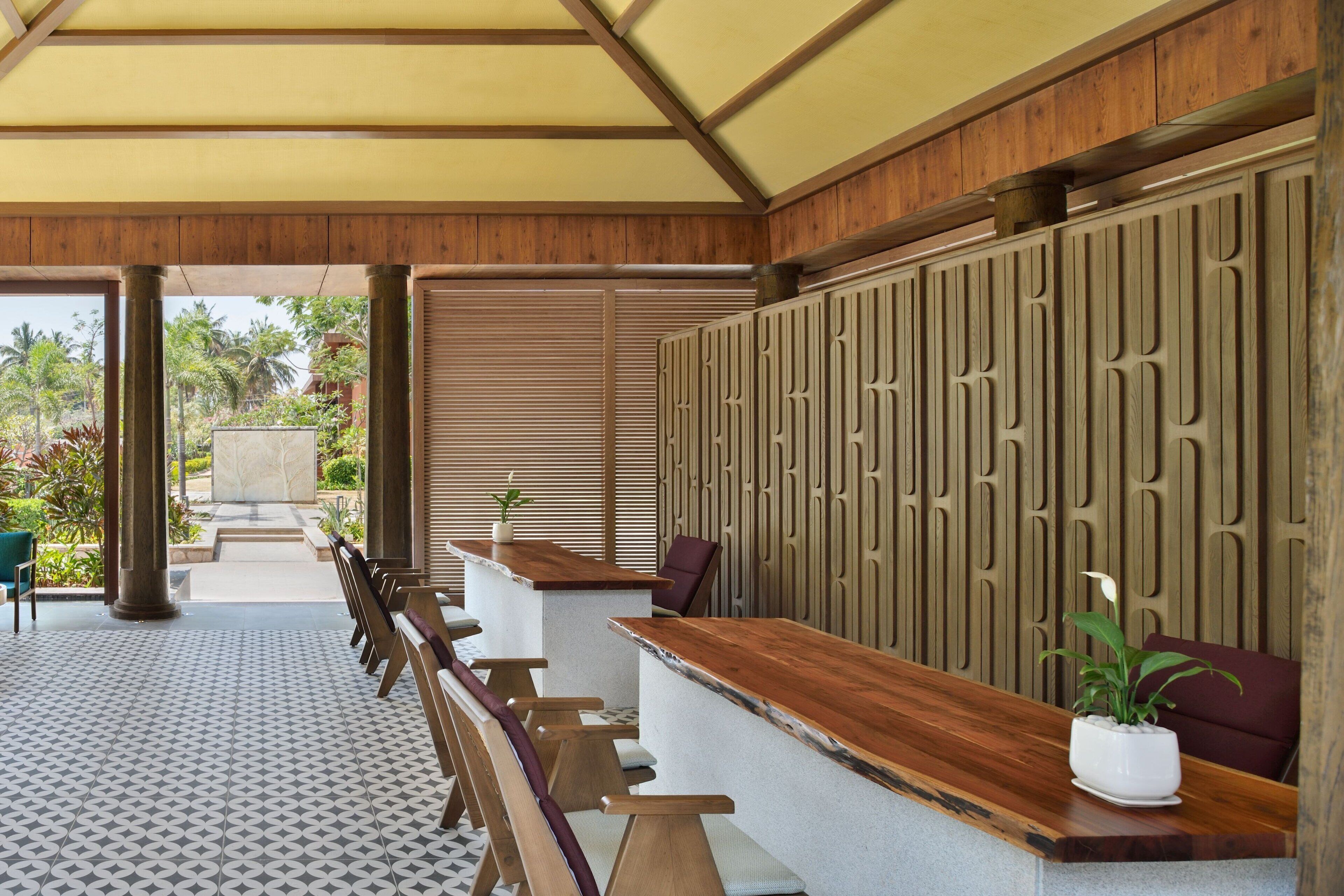 Un área de recepción con un mostrador de madera, varias opciones de asientos acolchados y un panel decorativo en la pared.