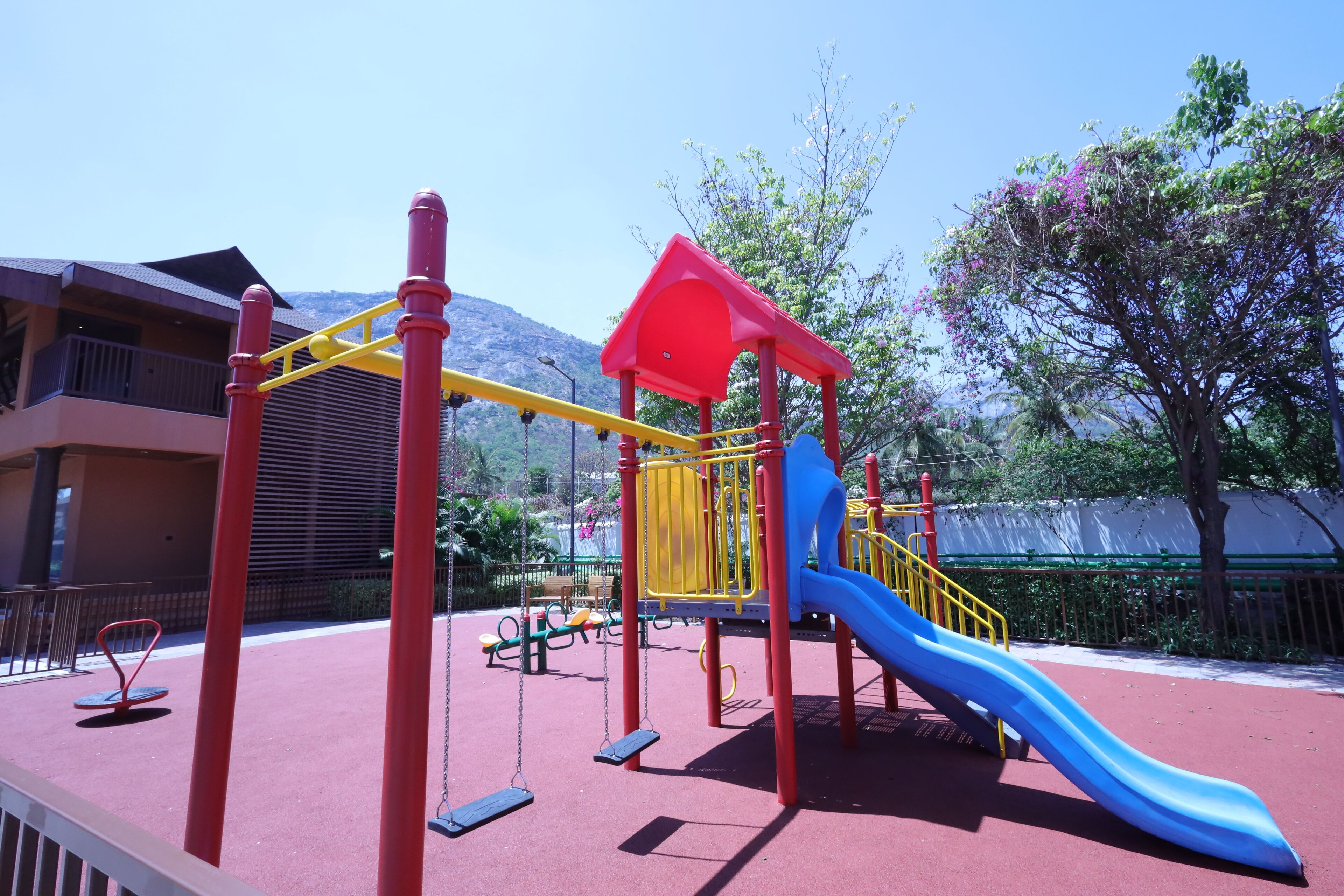 Un parque infantil con un tobogán azul y estructuras de juego en rojo y amarillo.