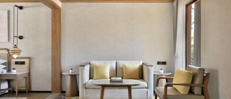 Una sala de estar moderna con un sofá, una silla, una mesita y un ventanal.