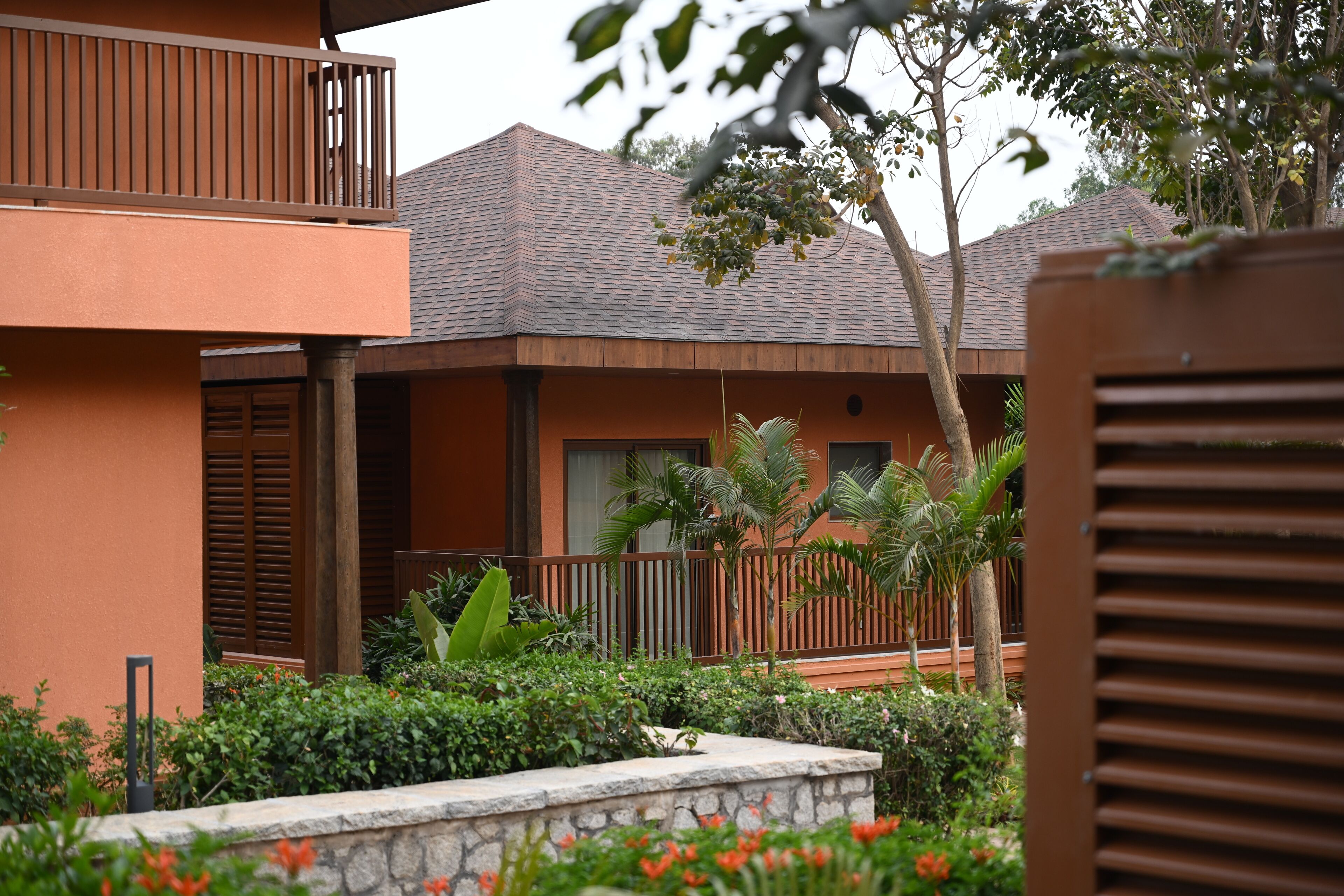 A multi-story building with balconies, a stone pathway, and tropical plants.