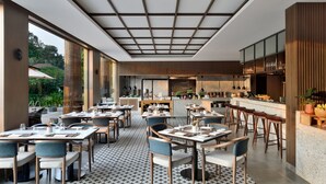 A modern restaurant with a central bar, dining tables, and chairs.
