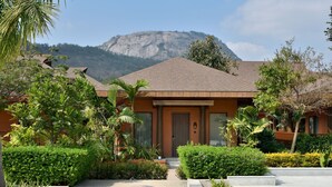 A modern building with a brown roof and a mountain in the background.