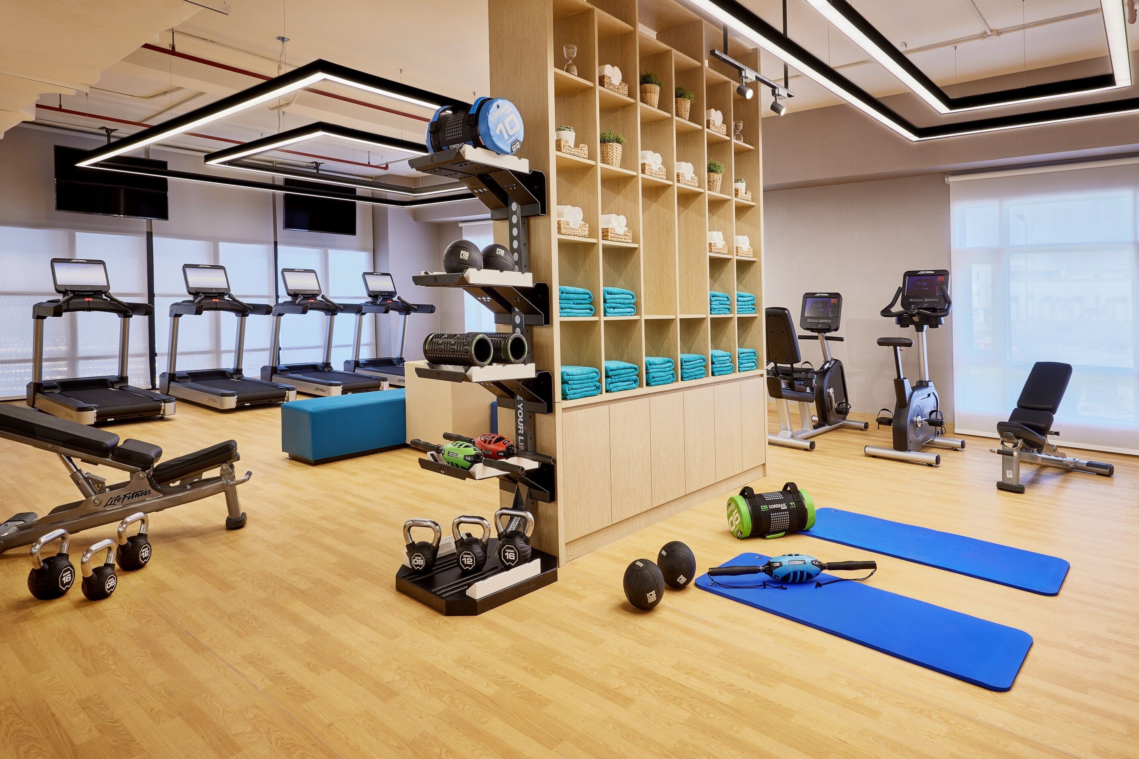 Et fitnesscenter med løbebånd, styrkemaskiner og håndvægte.