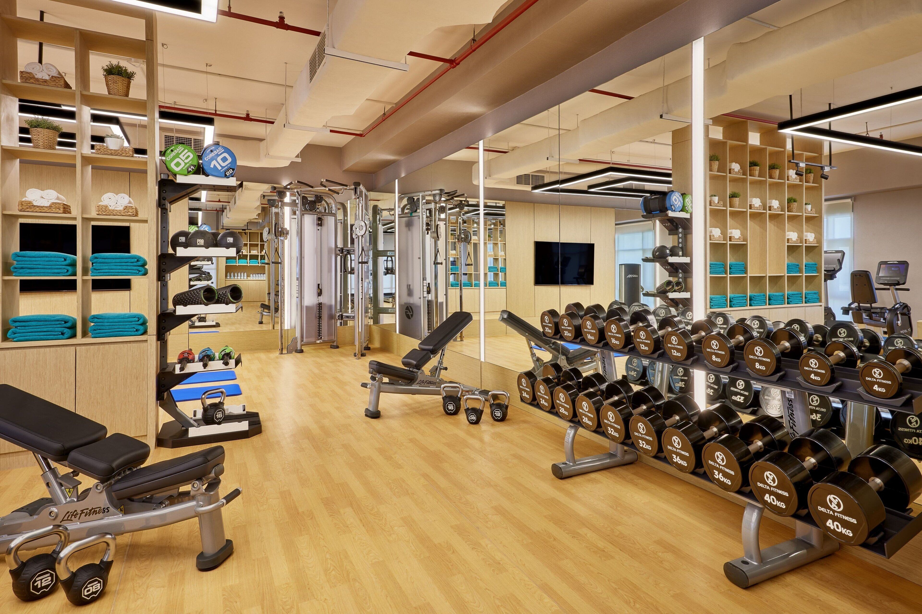 Un gimnasio con equipo de levantamiento de pesas, bancos y mancuernas.
