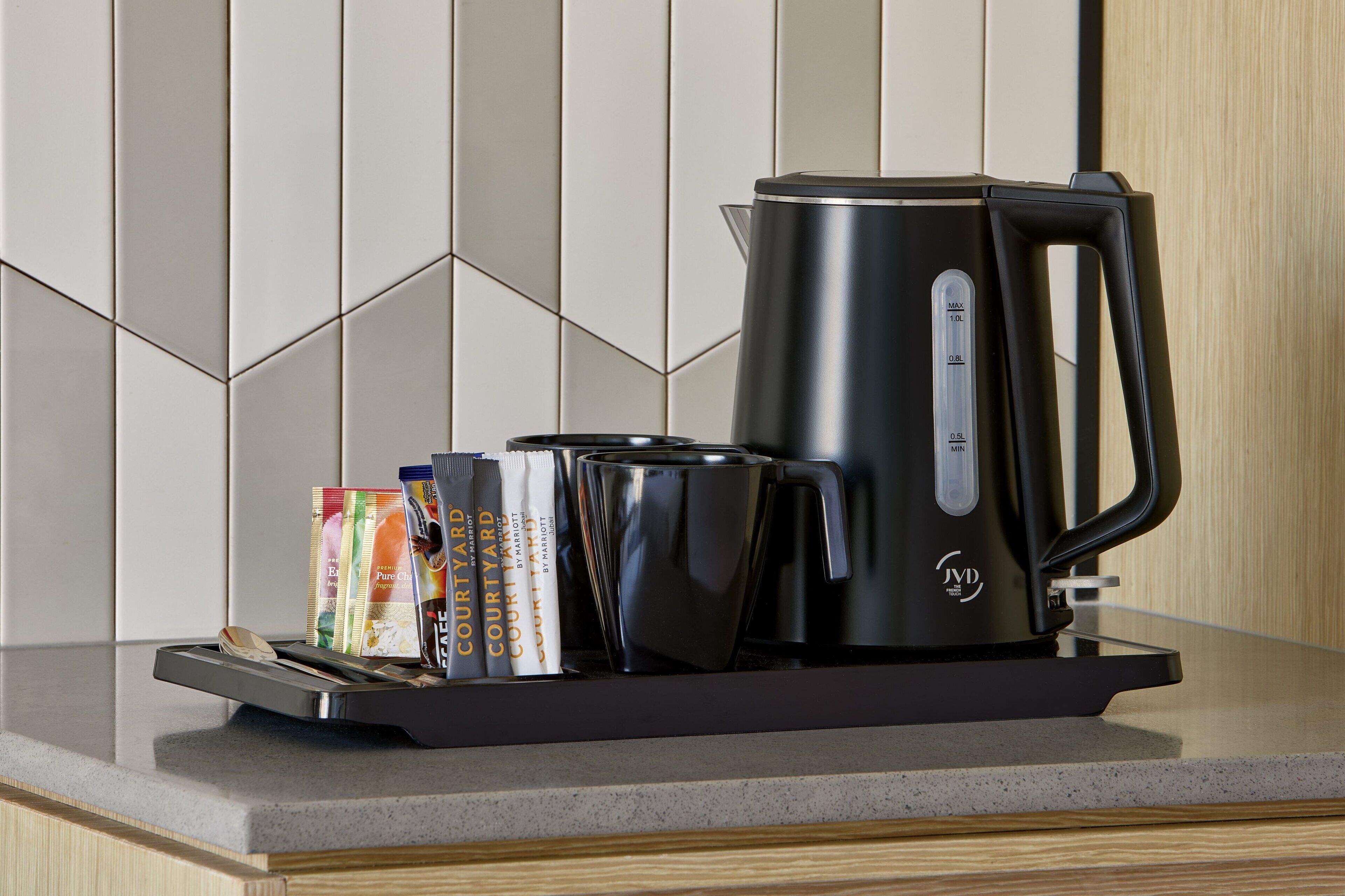 Une cuisine moderne équipée d’une machine à café, d’un présentoir avec des capsules de café et d’une tasse.