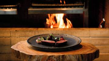 A wooden table with a plate of food in front of a fireplace.