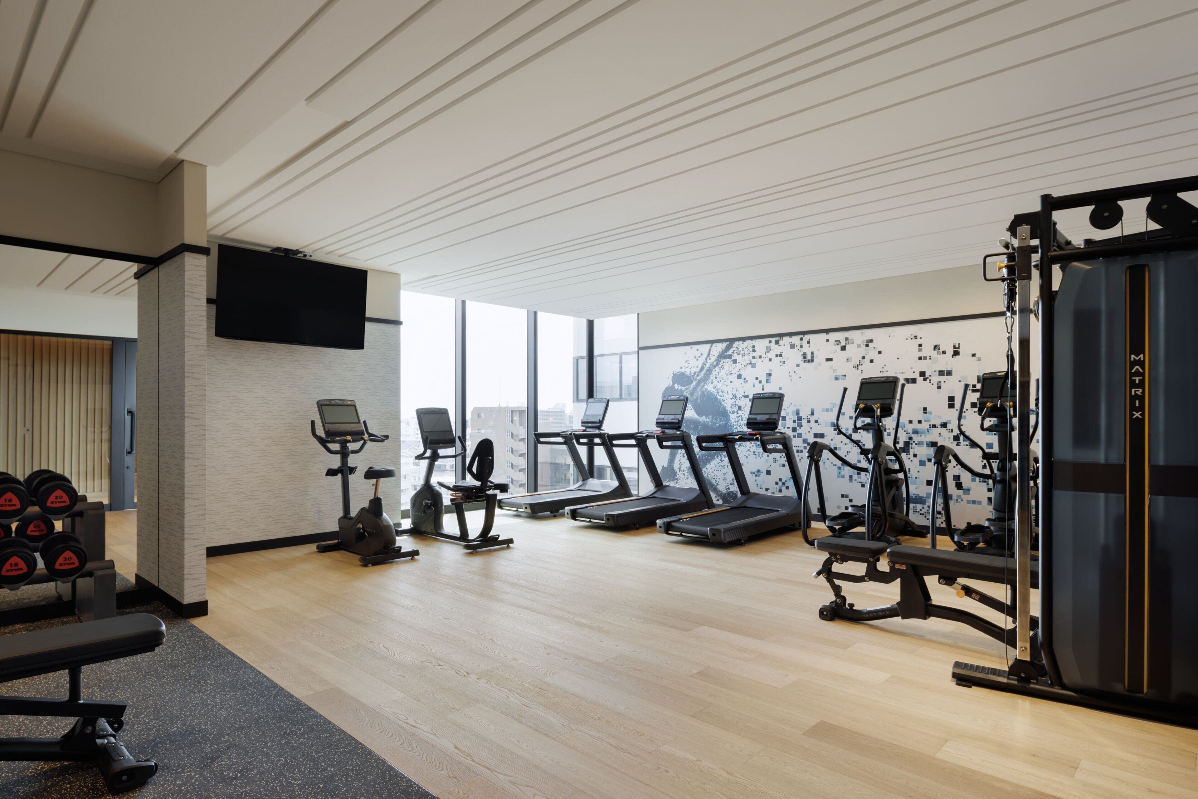 A modern gym with treadmills, elliptical machines, and weightlifting equipment.