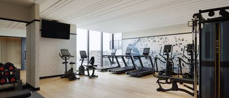 A modern gym with treadmills, elliptical machines, and weightlifting equipment.