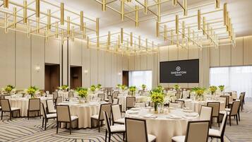 A conference room with round tables, chairs, and a large screen displaying 'Sheraton'.