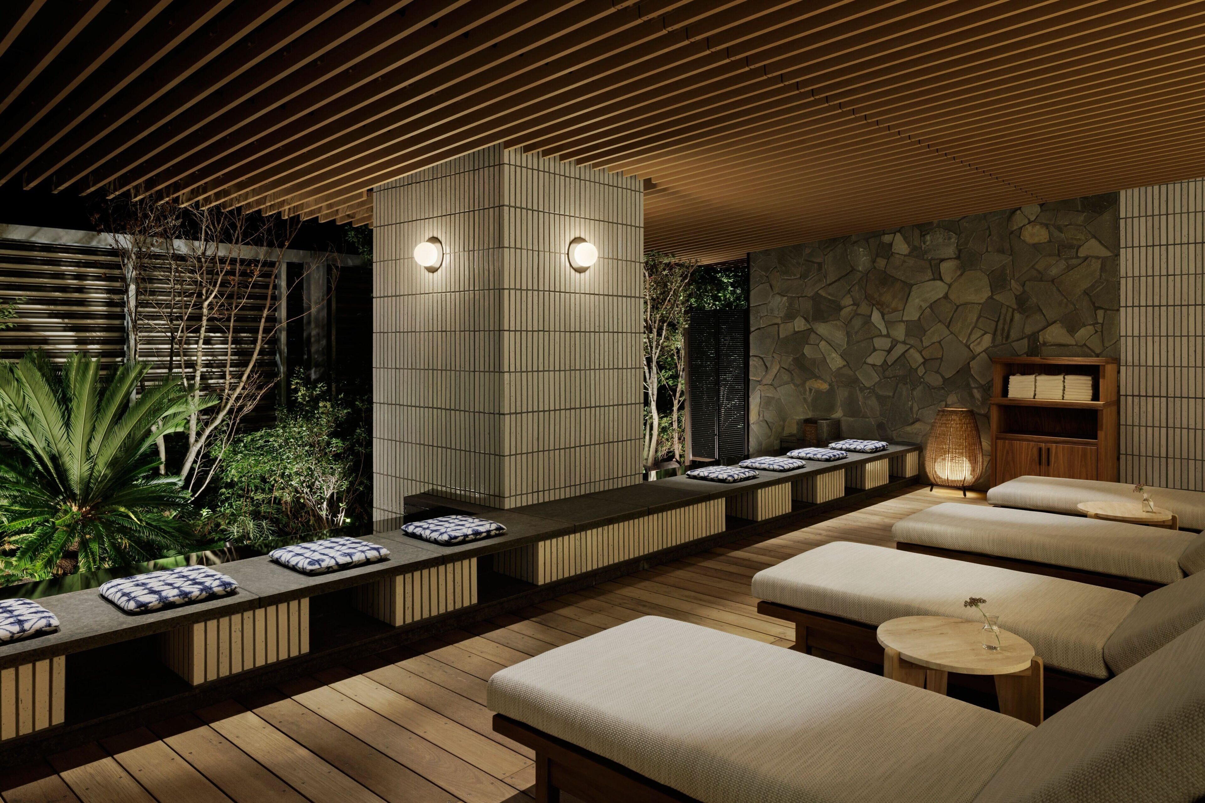 A spa area with wooden benches, a stone wall, and a ceiling with wooden slats.