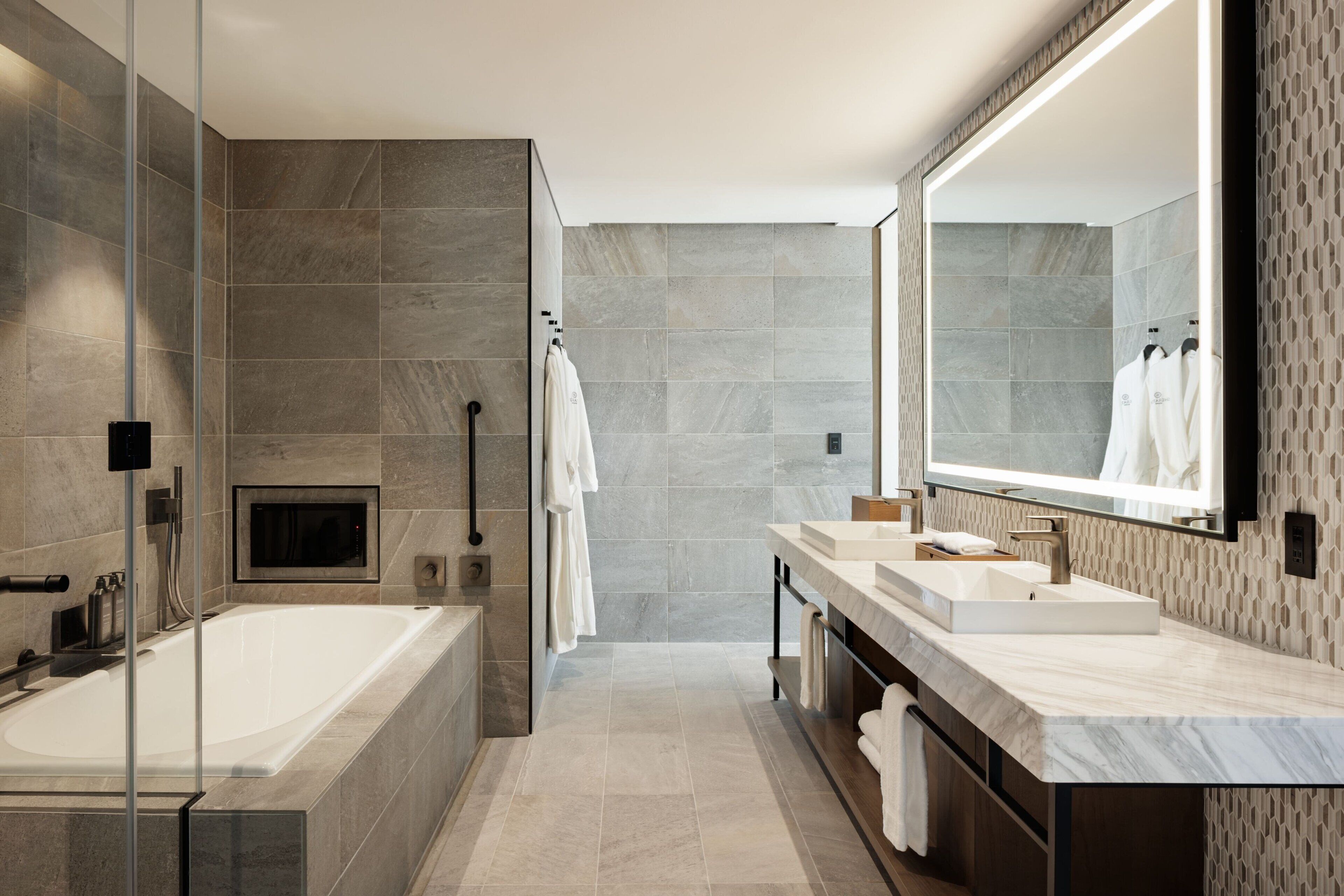 A modern bathroom with a large bathtub, a vanity with a mirror, and a shower area.